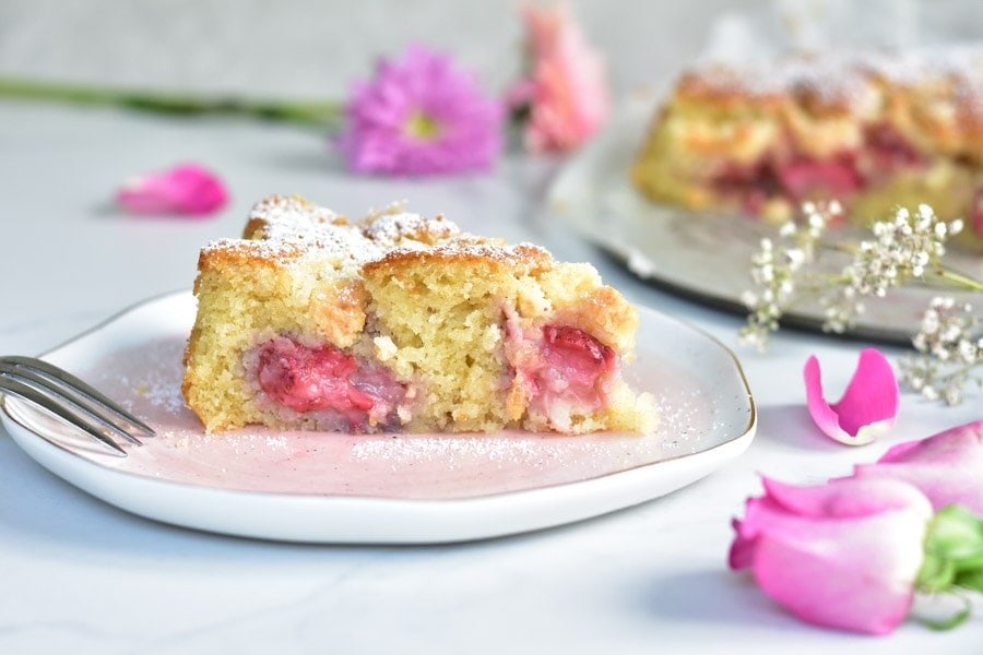 A slice of coconut cake with strawberries on a rose plate.