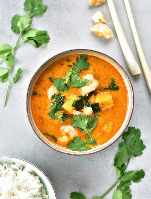 Thai red curry with shrimp and spinach in a grey bowl.