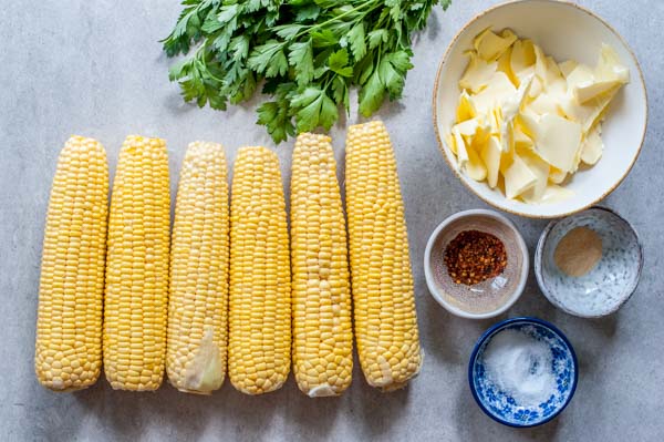 ingredients for oven roasted corn on a cob with herb and chili butter on a table