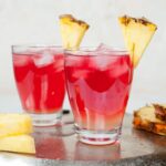 Two glasses with malibu bay breeze, rim decorated with a pineapple wedge.