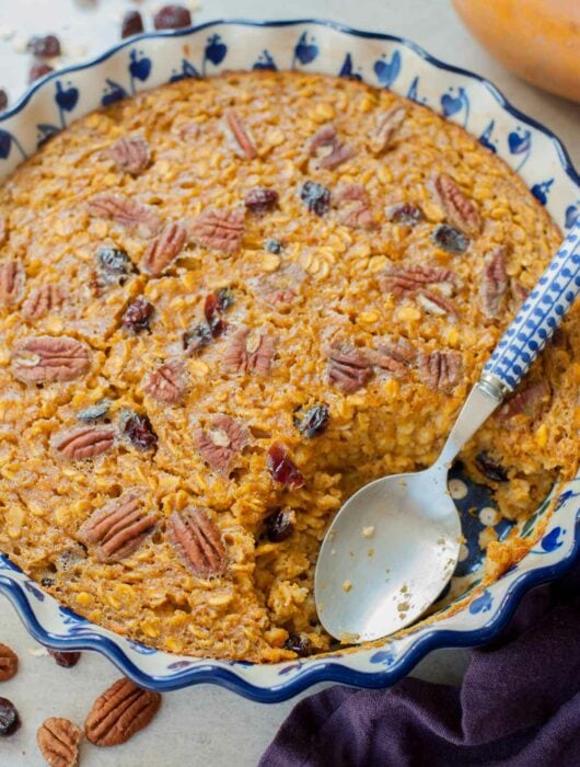 A close up picture of baked pumpkin oatmeal in a baking dish with a serving missing.