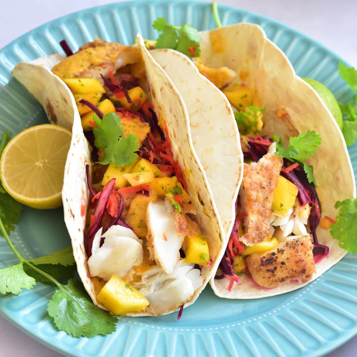 Fish tacos with mango salsa on a blue plate.