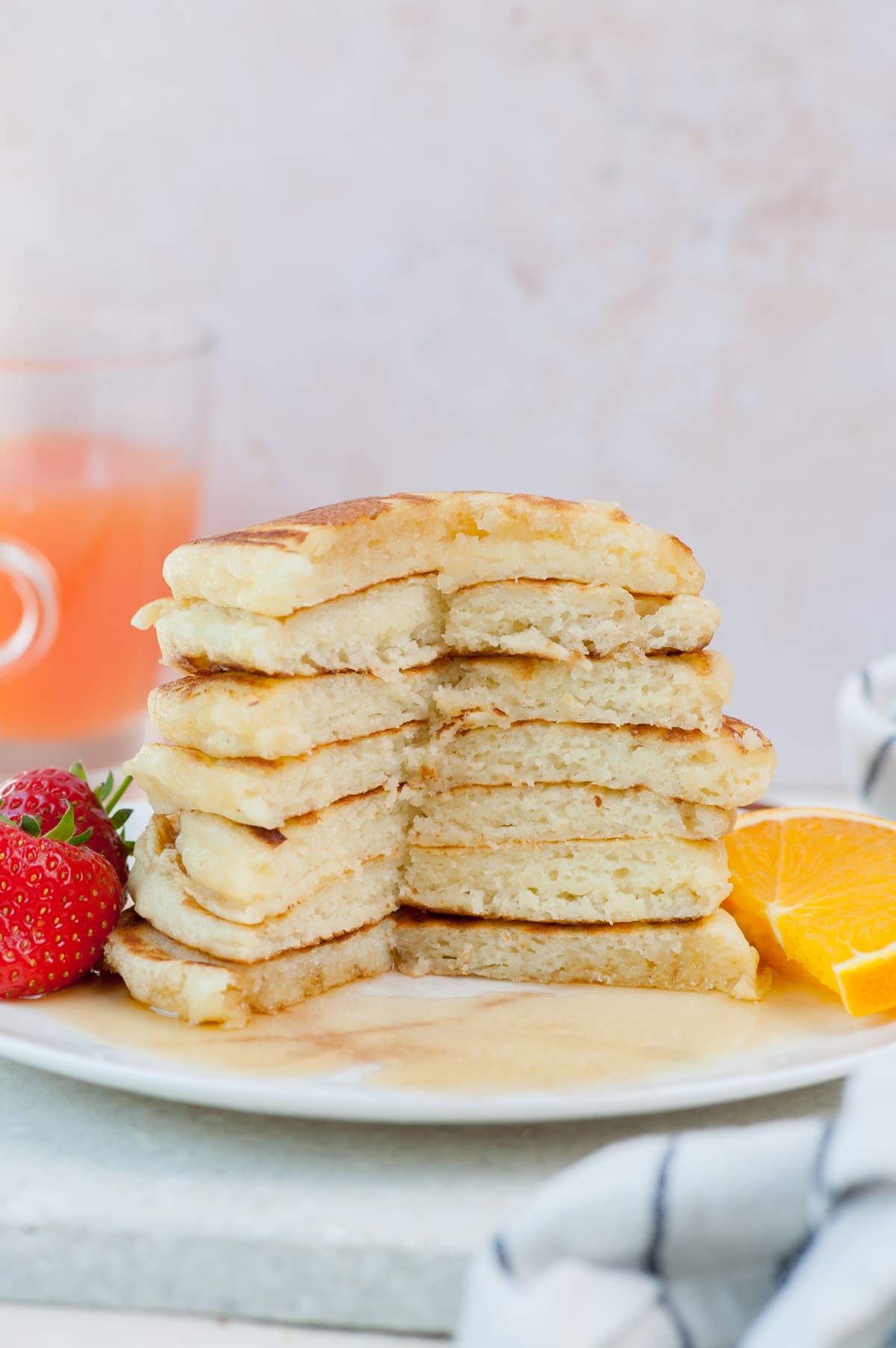 A stack of buttermilk pancakes with a part missing on a white plate.