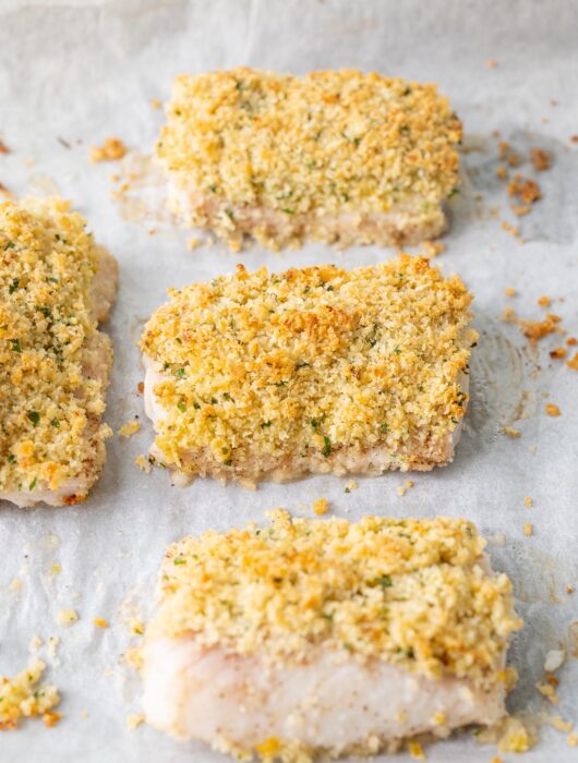 Parmesan crusted cod fillets on a baking sheet.
