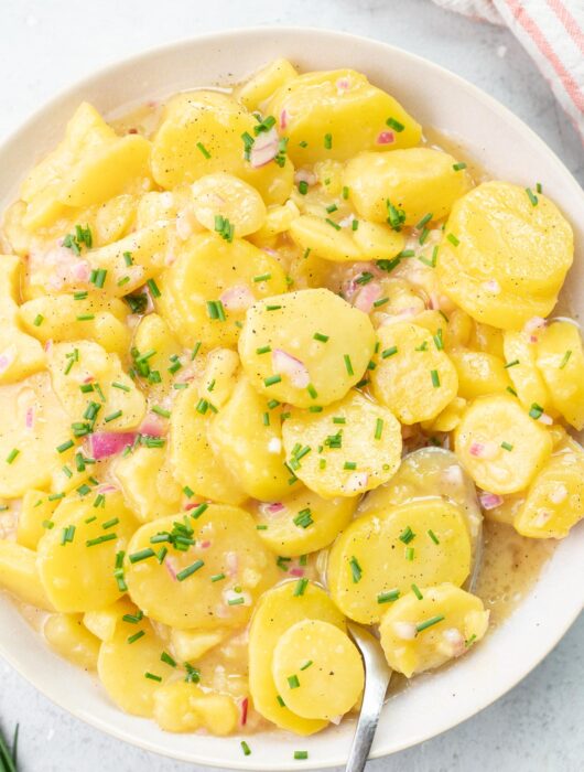 Austrian potato salad in a beige bowl.