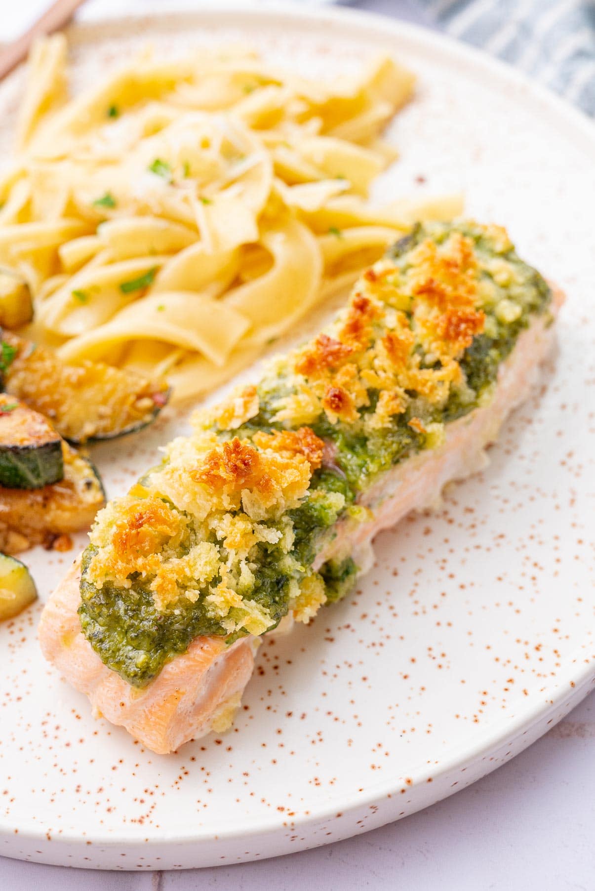 Baked pesto salmon on a white plate.