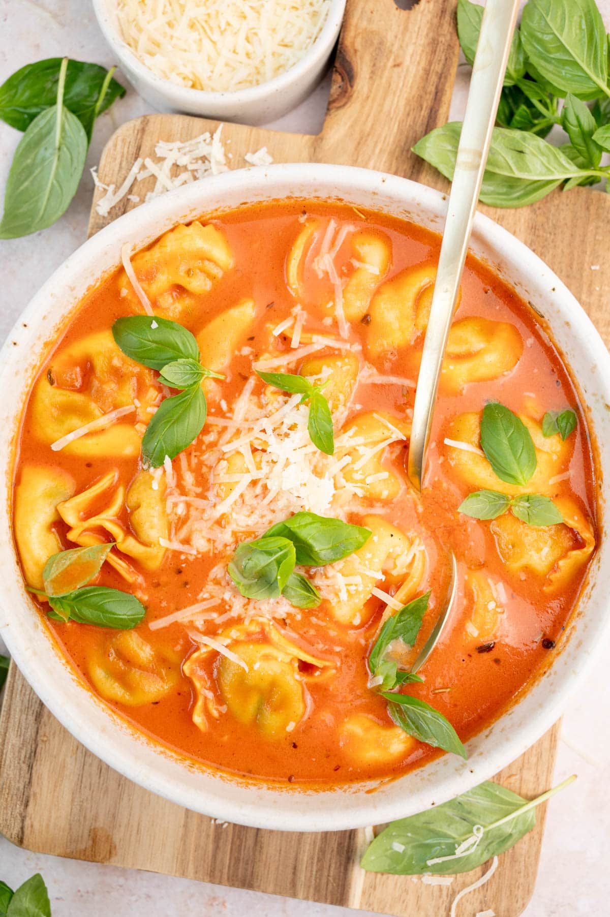 Tomato tortellini soup in a white bowl.