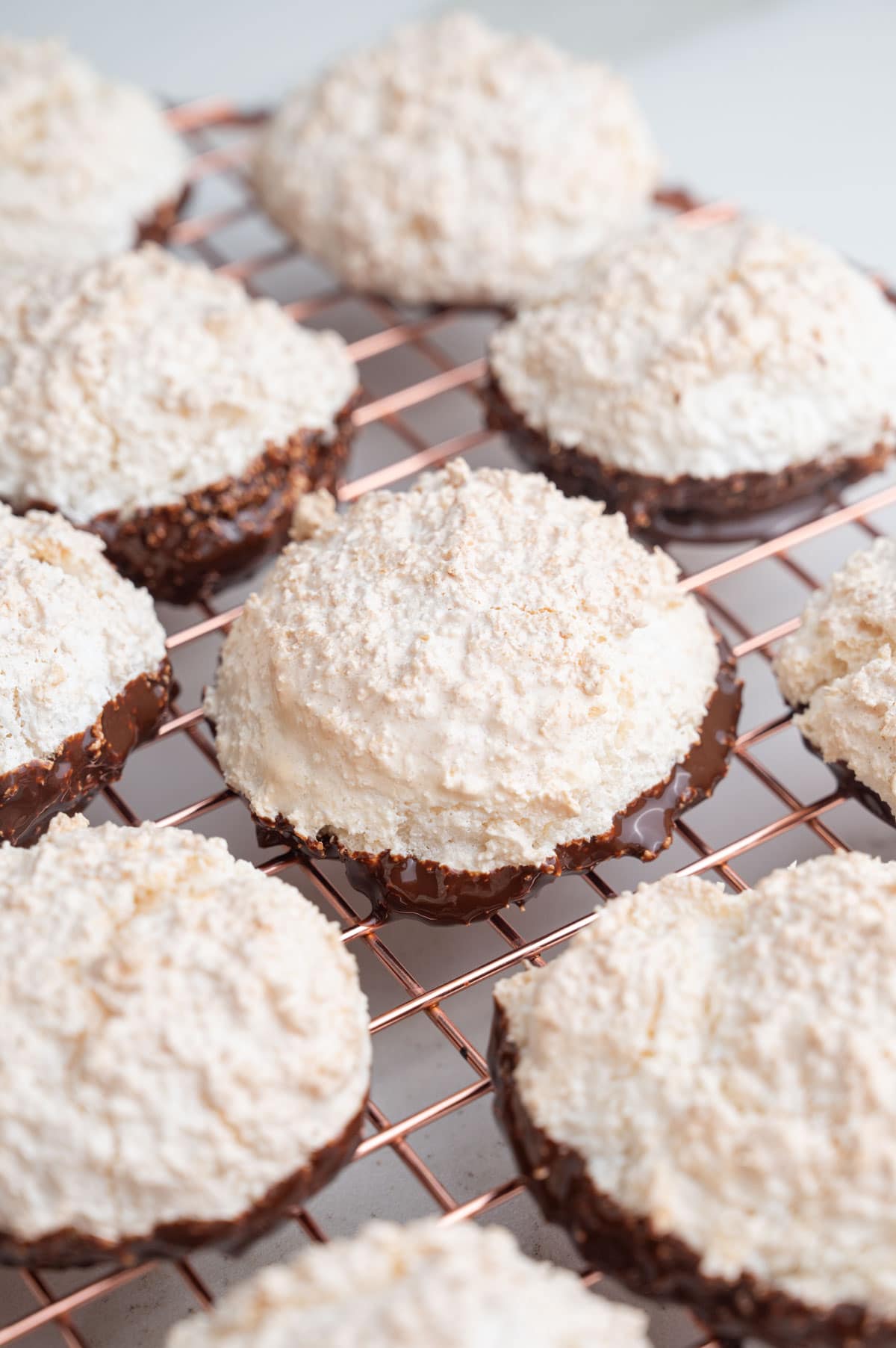 Kokosmakronen dipped in chocolate on a gold cooling rack.