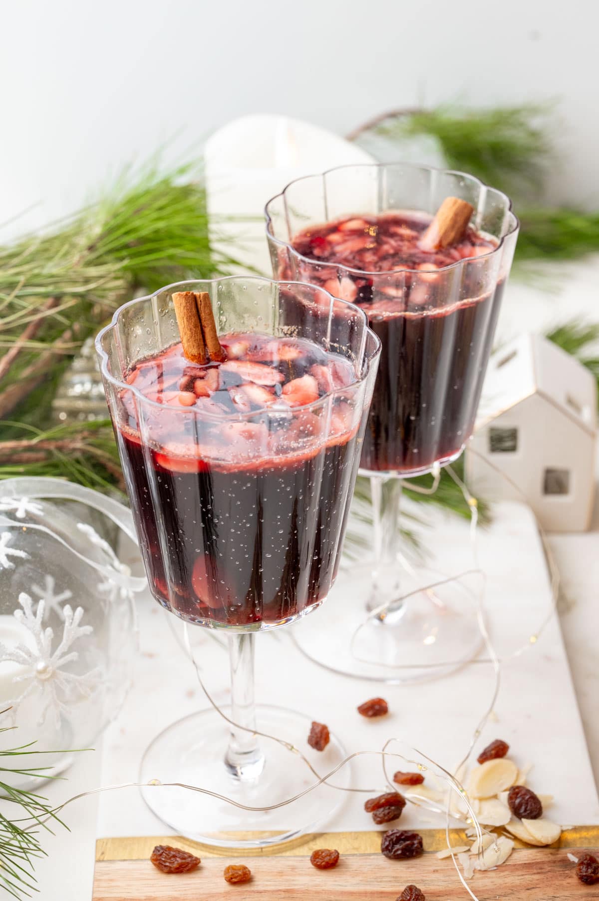 Two glasses with Glogg - Scandinavian mulled wine on a white board. Christmas decorations in the background.