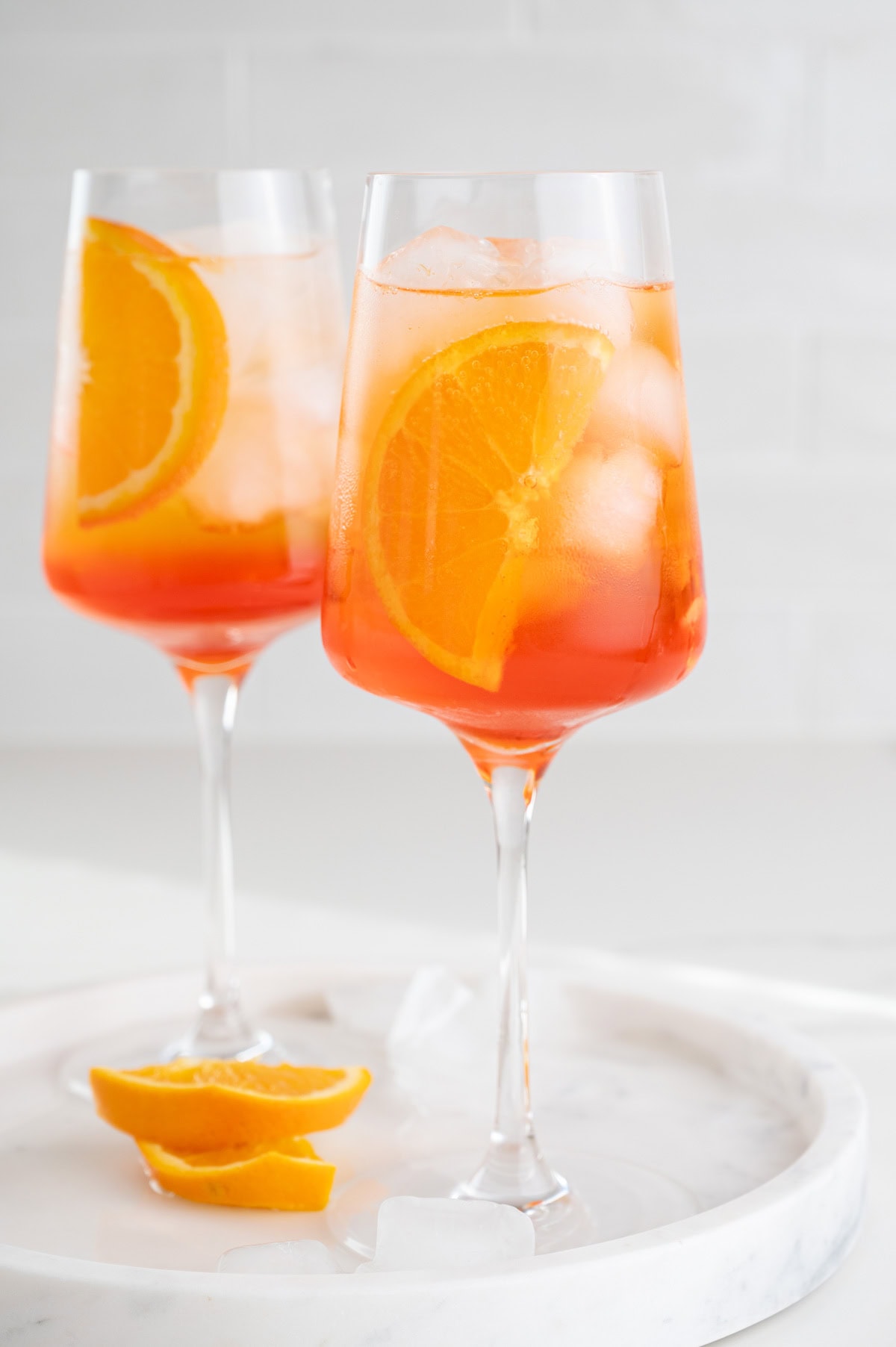 Two glasses with Aperol Spritz cocktail garnished with orange slices.