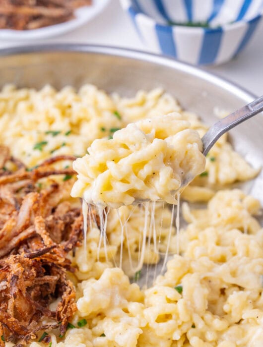 Käsespätzle on a spoon and in a frying pan.