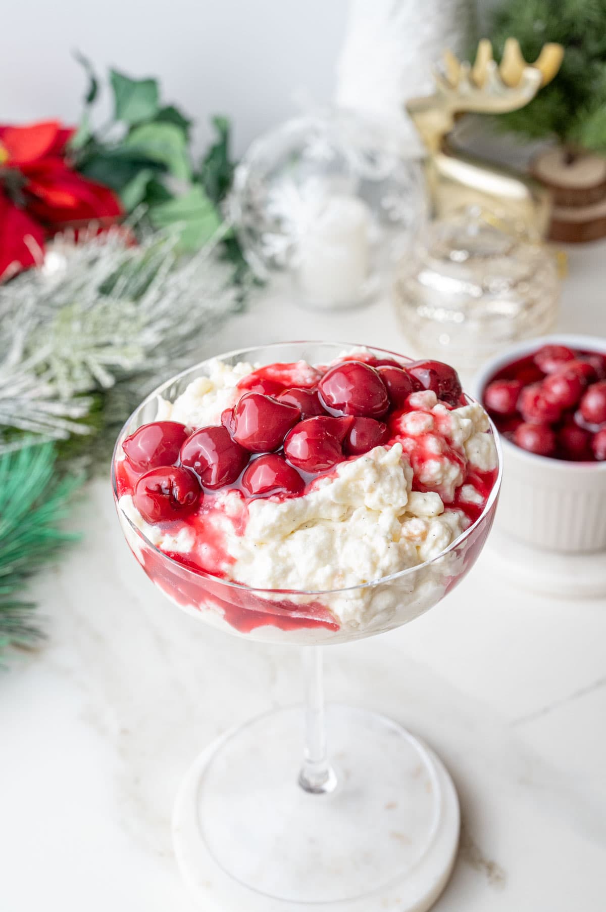 Risalamande with cherry sauce in a cocktail glass. Christmas decorations in the background.