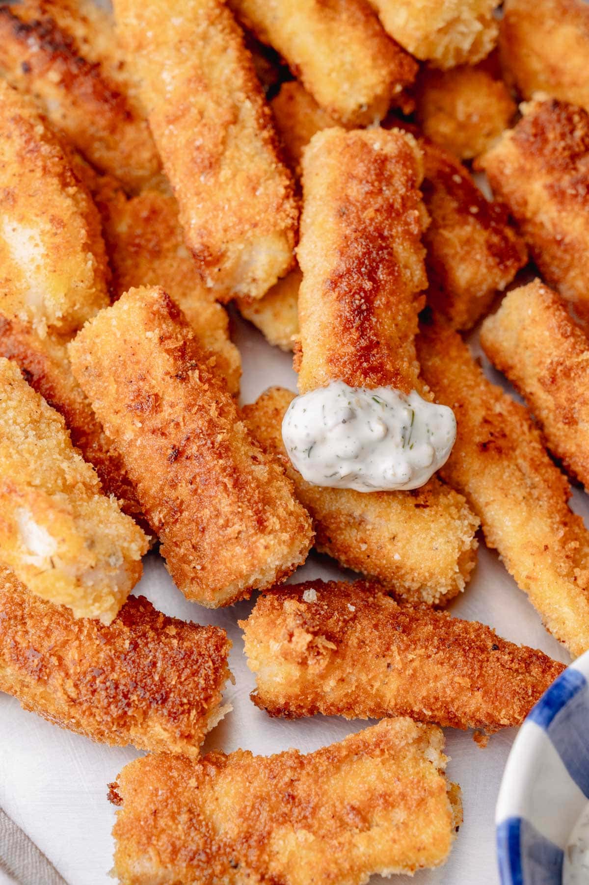 Close-up of crunchy homemade fish sticks topped with creamy tartar sauce.
Ask ChatGPT