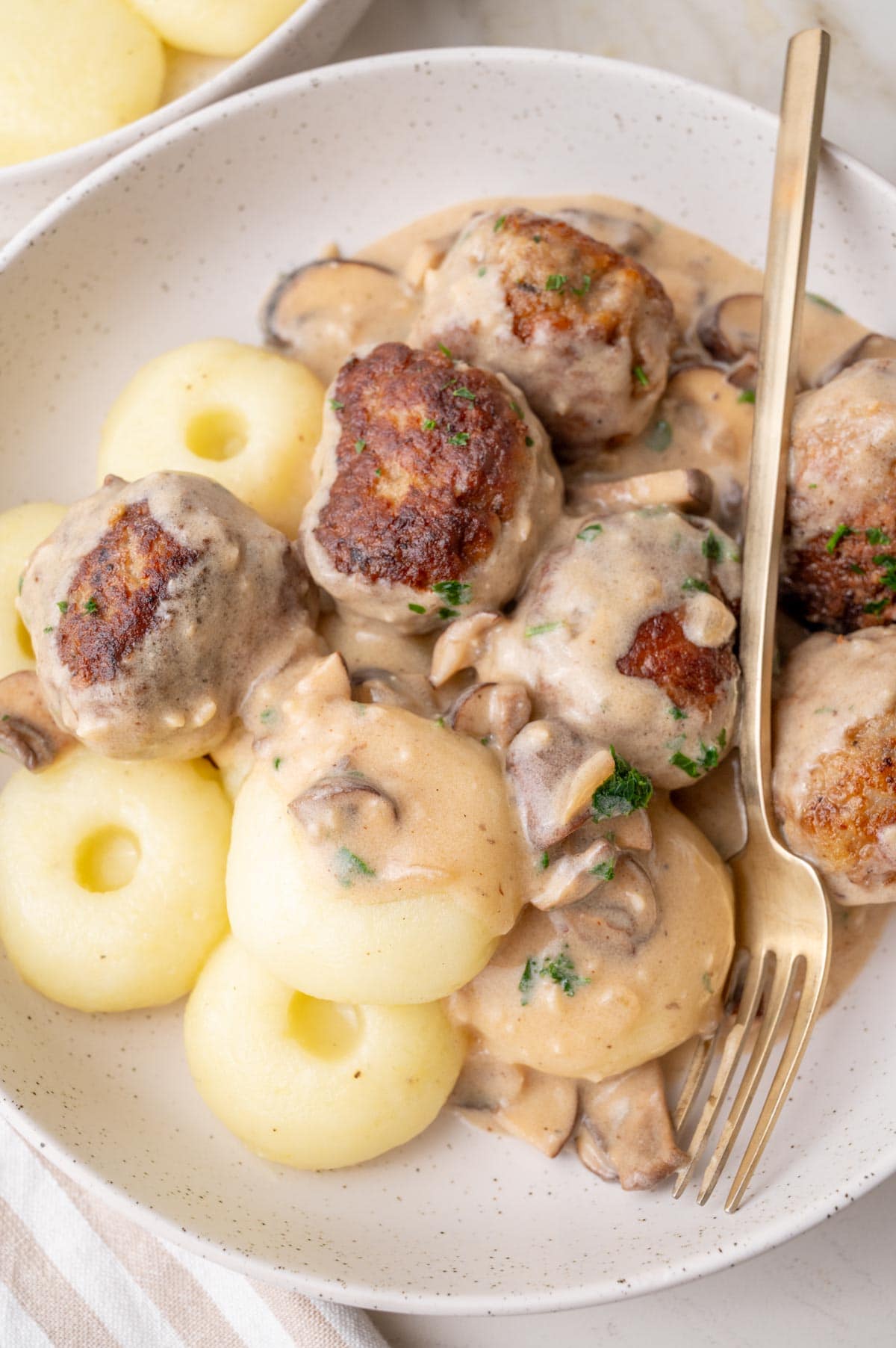 Polish meatballs with mushroom sauce served with Silesian dumplings on a white plate.