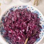 Danish red cabbage in a white bowl with blue flowers. Christmas decorations in the background.