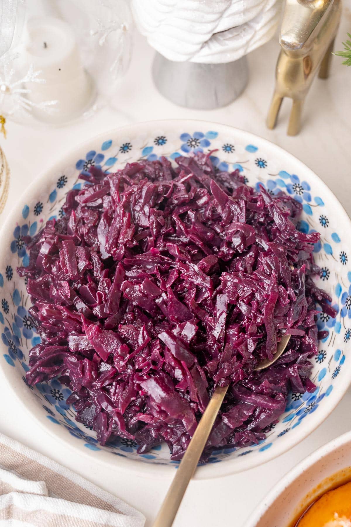 Danish red cabbage in a white bowl with blue flowers. Christmas decoration in the background.