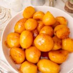 Danish caramel potatoes in a white bowl. Christmas decoration in the background.